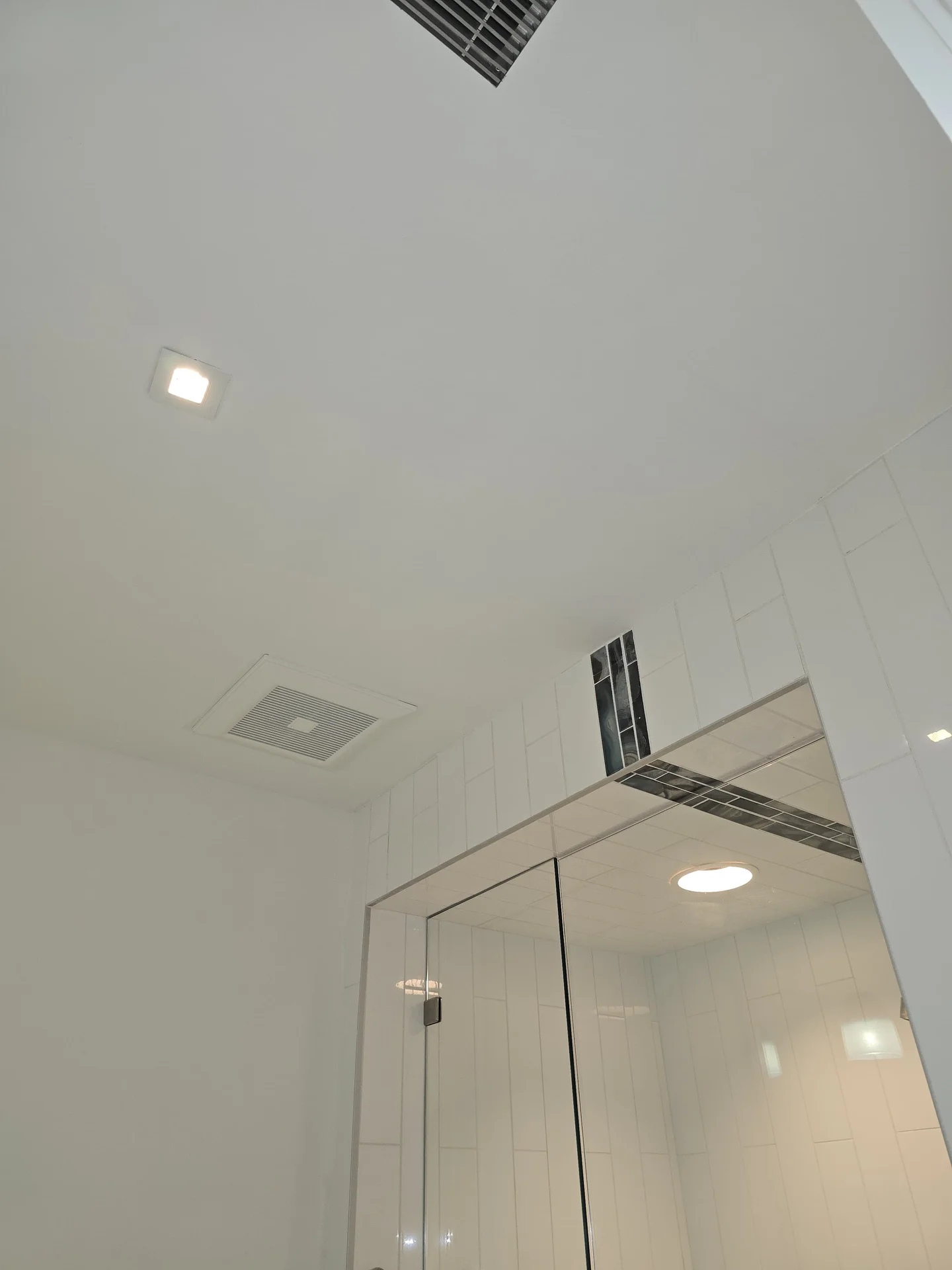 Walk-in shower finished in white tile with a glass enclosure