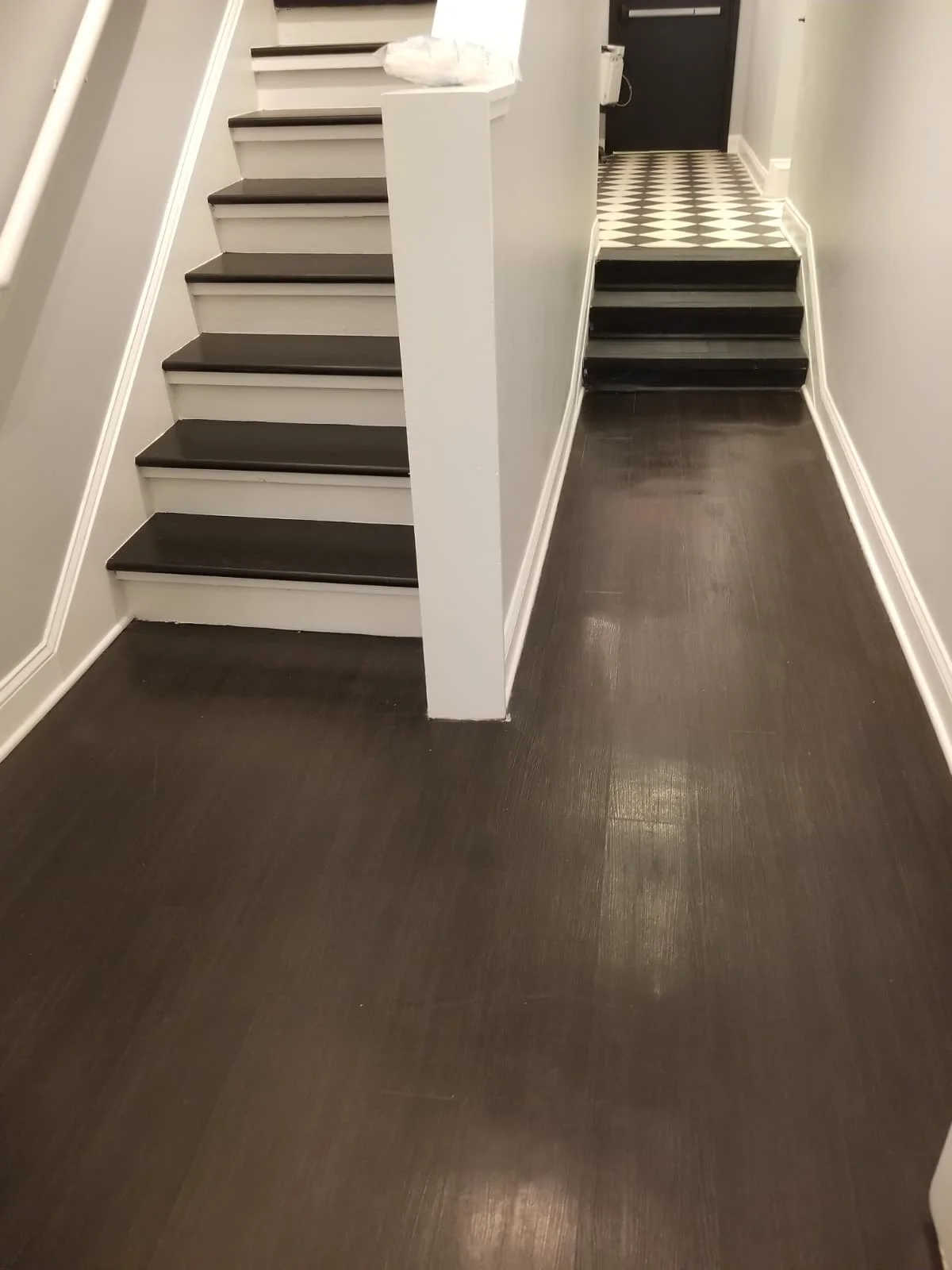 Dark hardwood floor with a painted staircase and checkered-tile landing