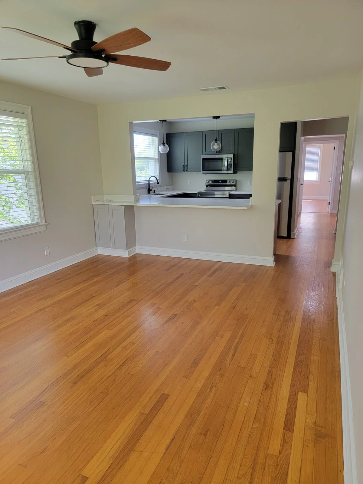 Finished open-plan living area with hardwood floor opening to a remodeled kitchen