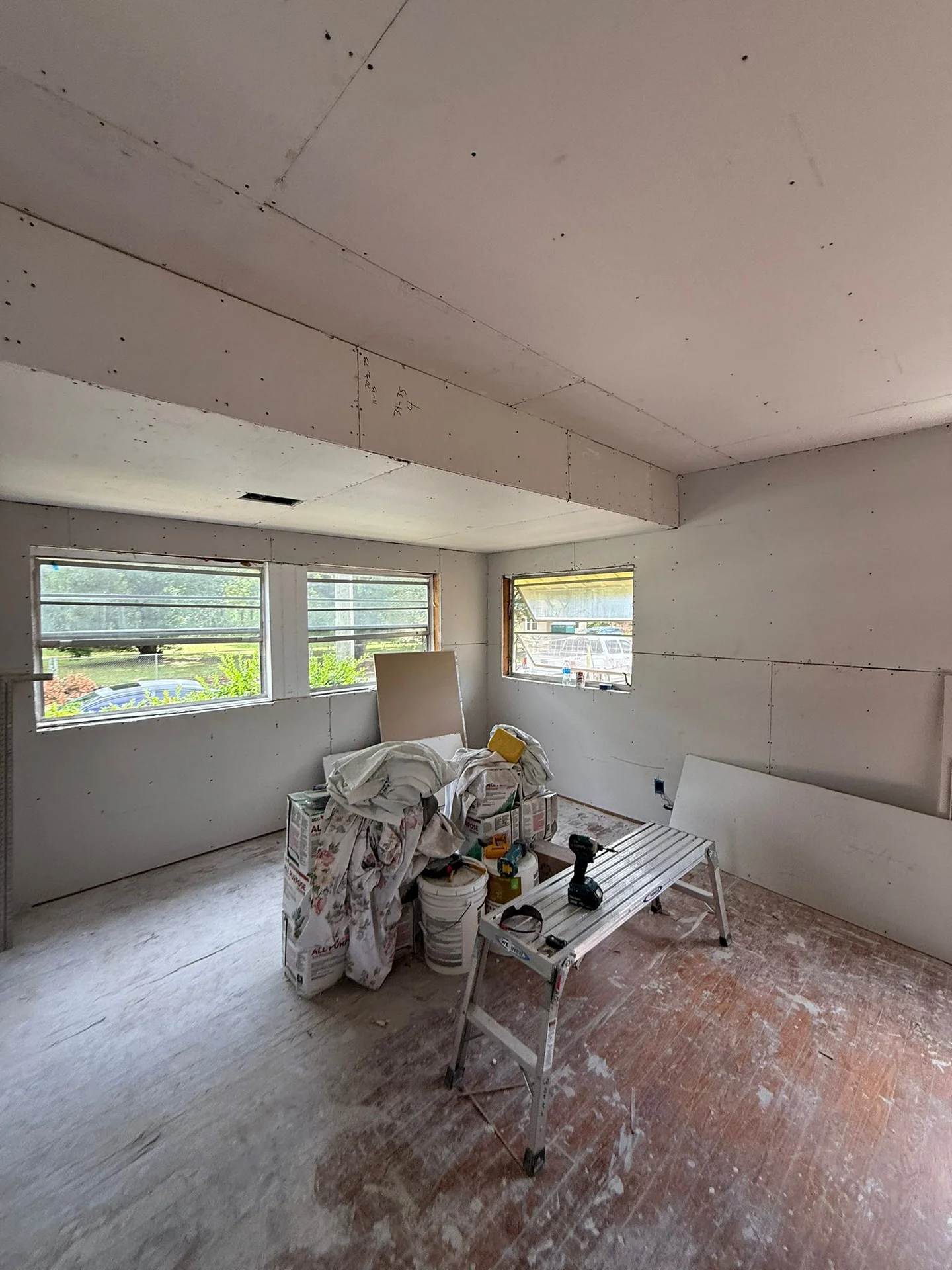 Room mid-remodel at the drywall stage with newly framed windows